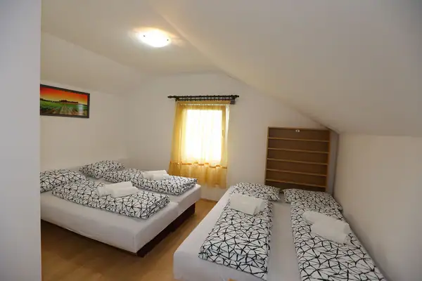 Potkrovna soba sa više kreveta i prozorom